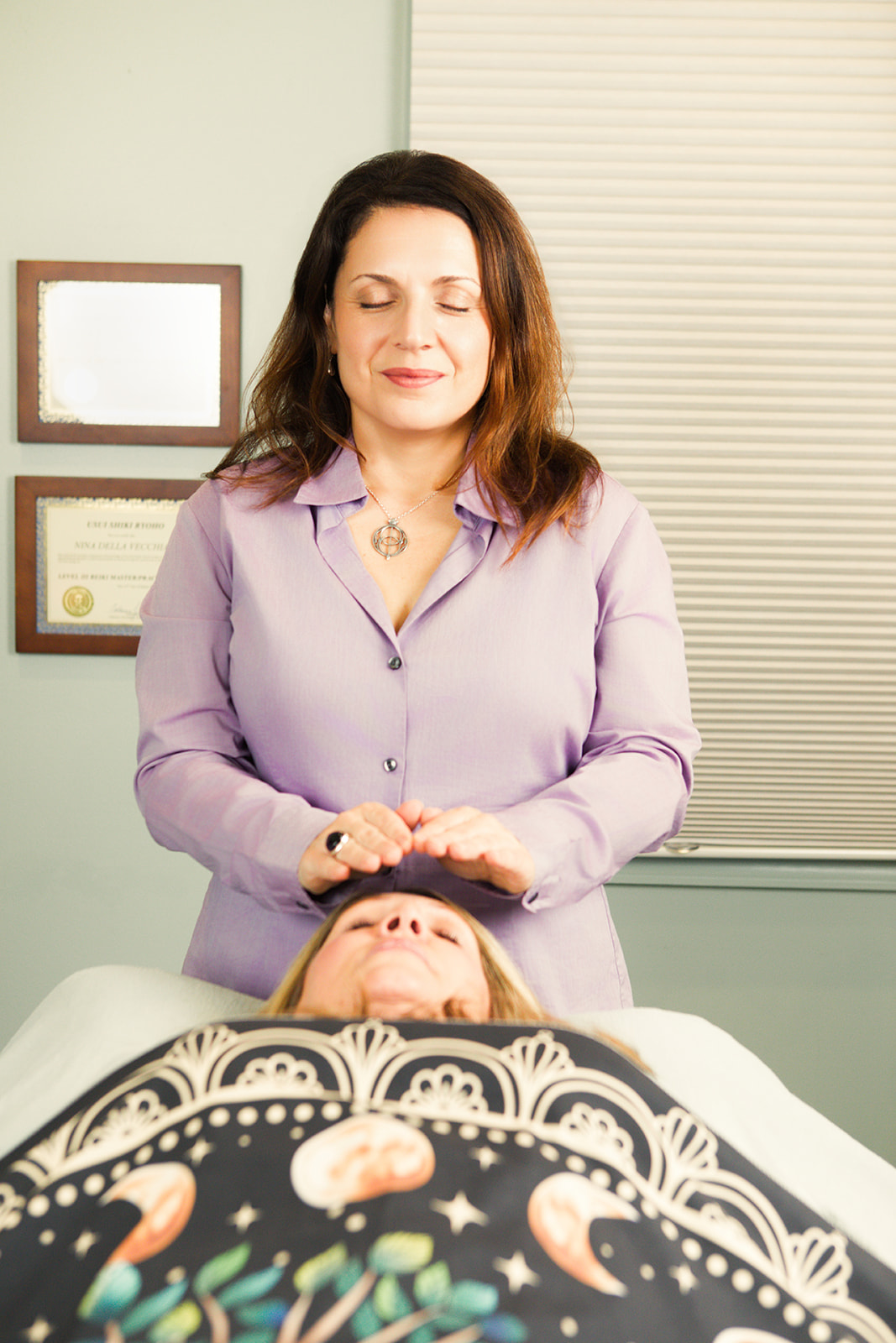 Nina resting her hands gently at a client's head during a Reiki session