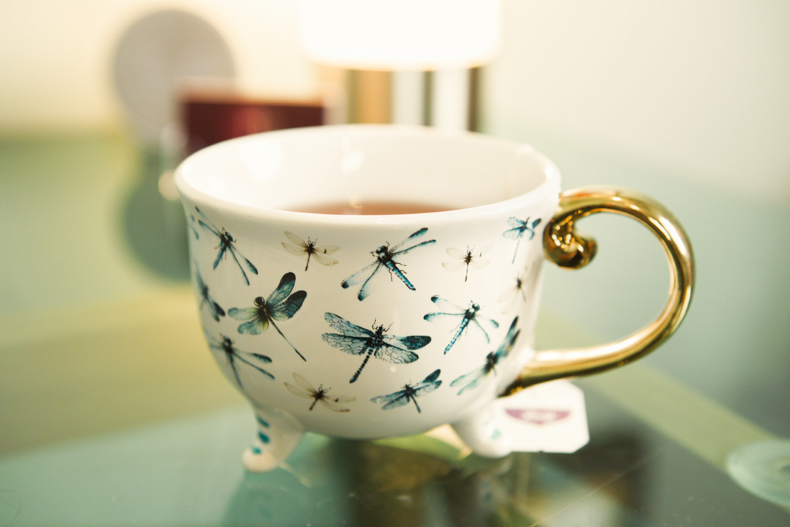 A teacup decorated with dragonflies, catching warm light