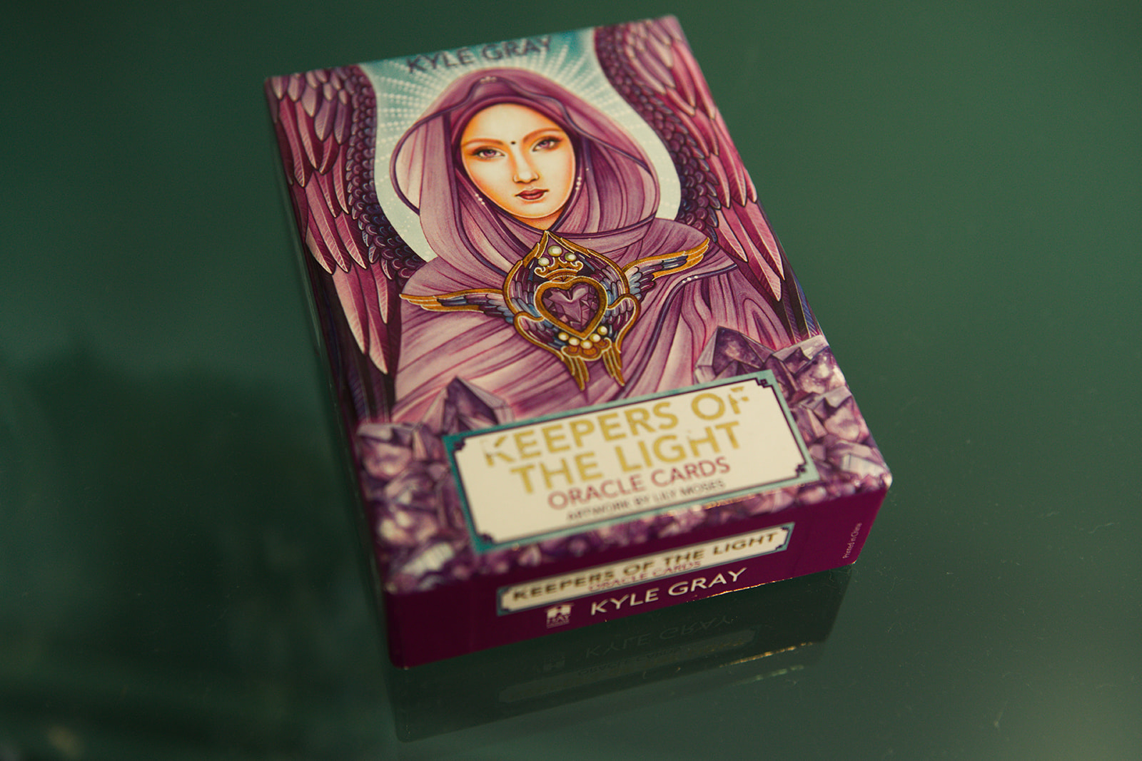 A deck of oracle cards resting on a deep green table