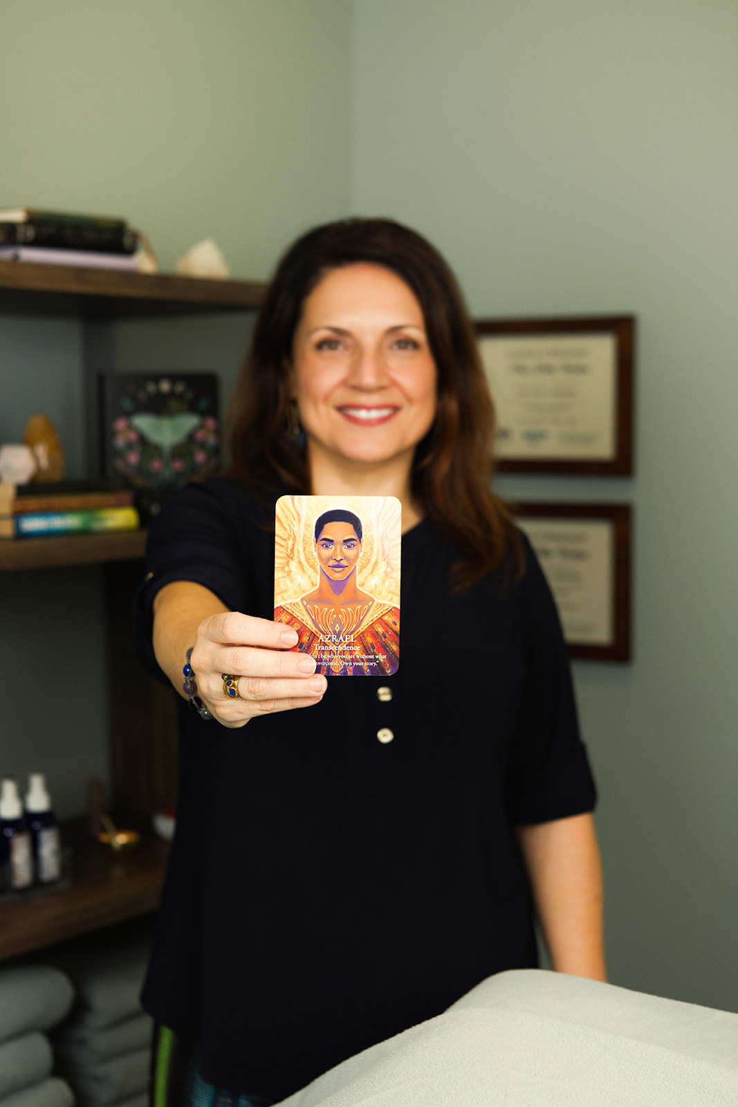 Nina smiling, holding out an oracle card in her treatment room