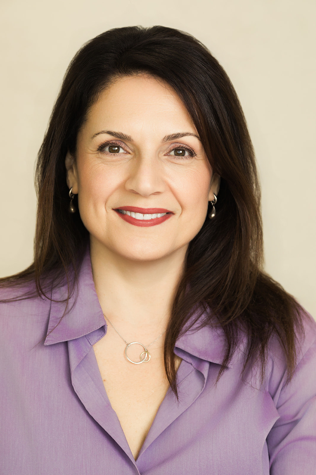 Portrait of Nina Della Vecchia smiling warmly in a lavender blouse