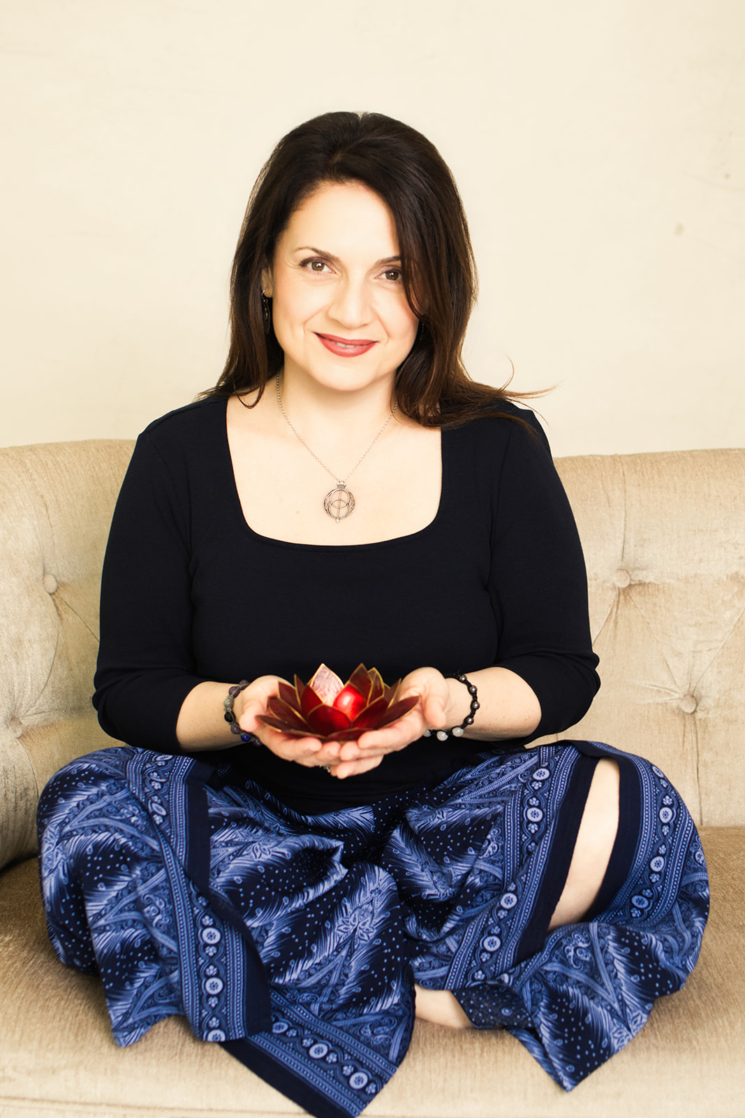 Nina smiling warmly, seated cross-legged and holding small crystals