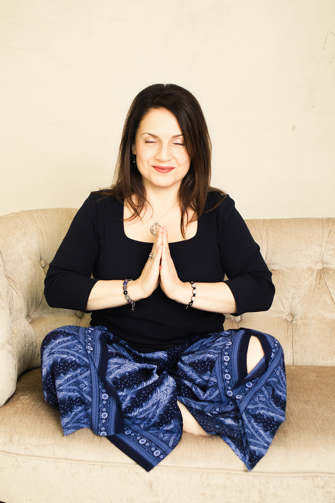 Nina seated in meditation with her hands together at her heart
